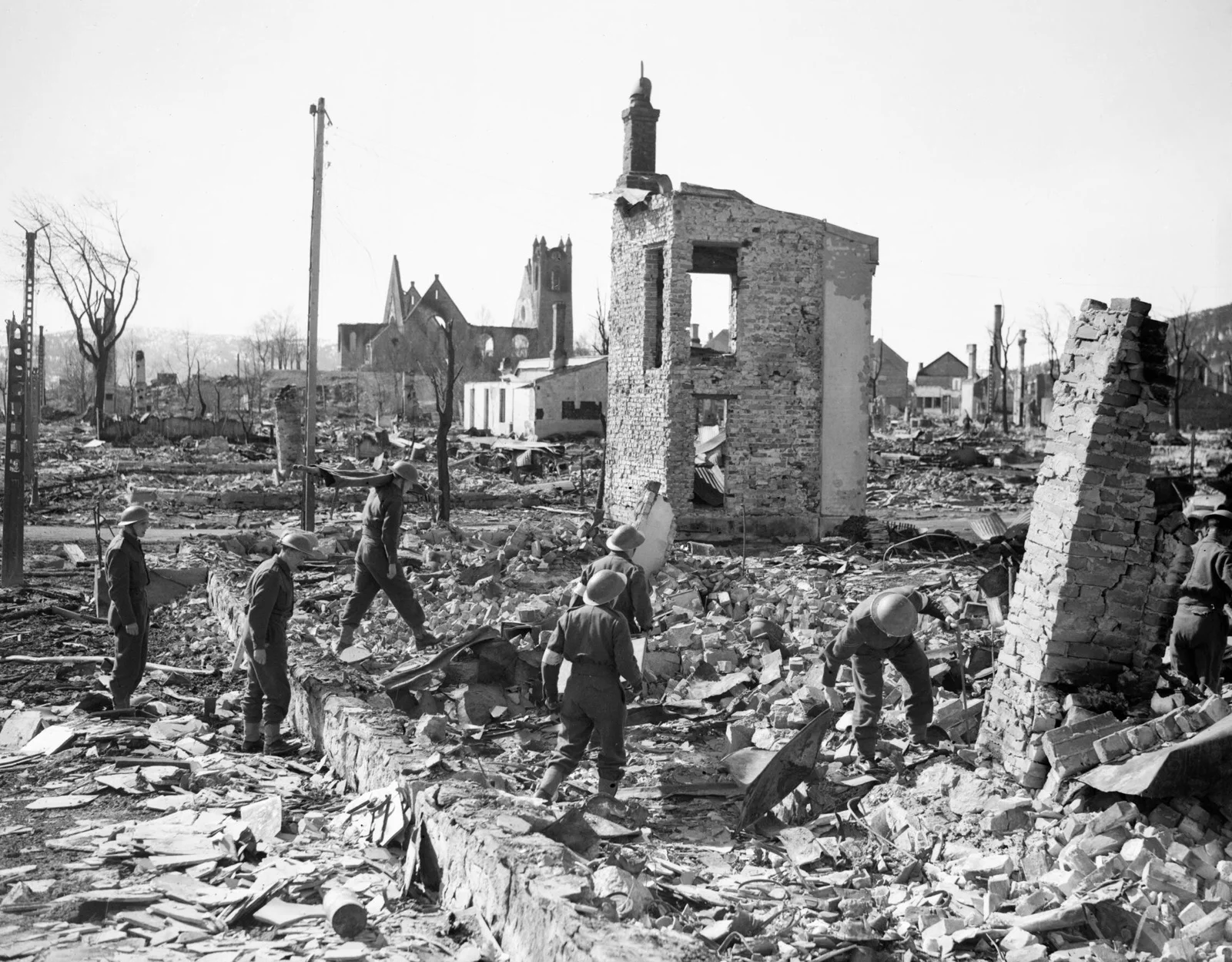 Des soldats britanniques marchent au milieu des décombres et des maisons éventrées de Namsos, en Norvège, après un bombardement aérien allemand, en avril 1940.
