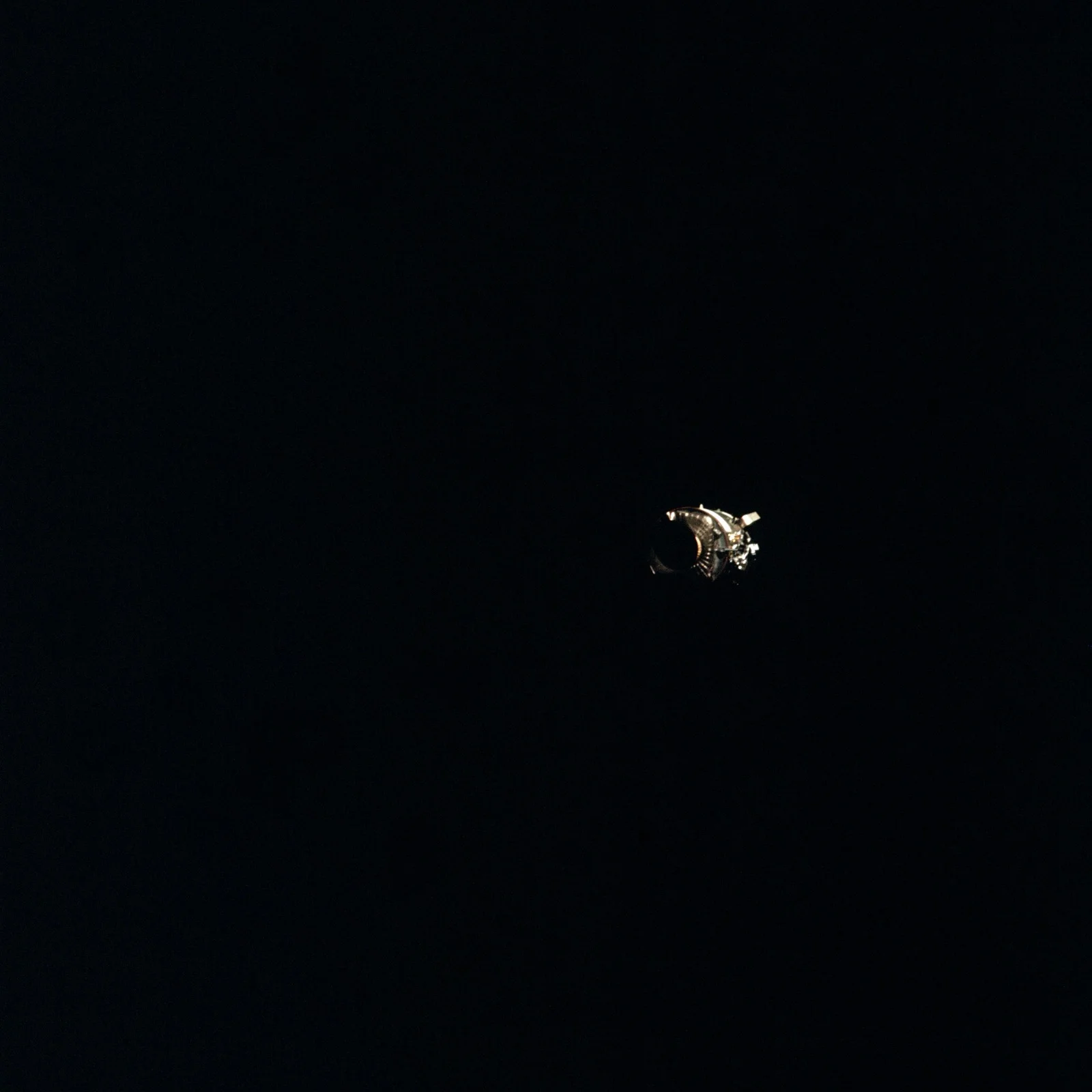 Le module de service d’Apollo 13, un panneau entier arraché, photographié après son largage, dérivant dans le vide spatial, le 17 avril 1970.
