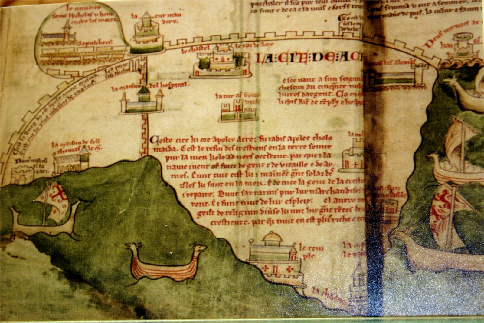 Plan médiéval de la cité d’Acre : une enceinte fortifiée bordée par la mer, ses tours et bâtiments légendés (« LA CITÉ DE ACRE »), avec plusieurs navires mouillés le long de la côte.