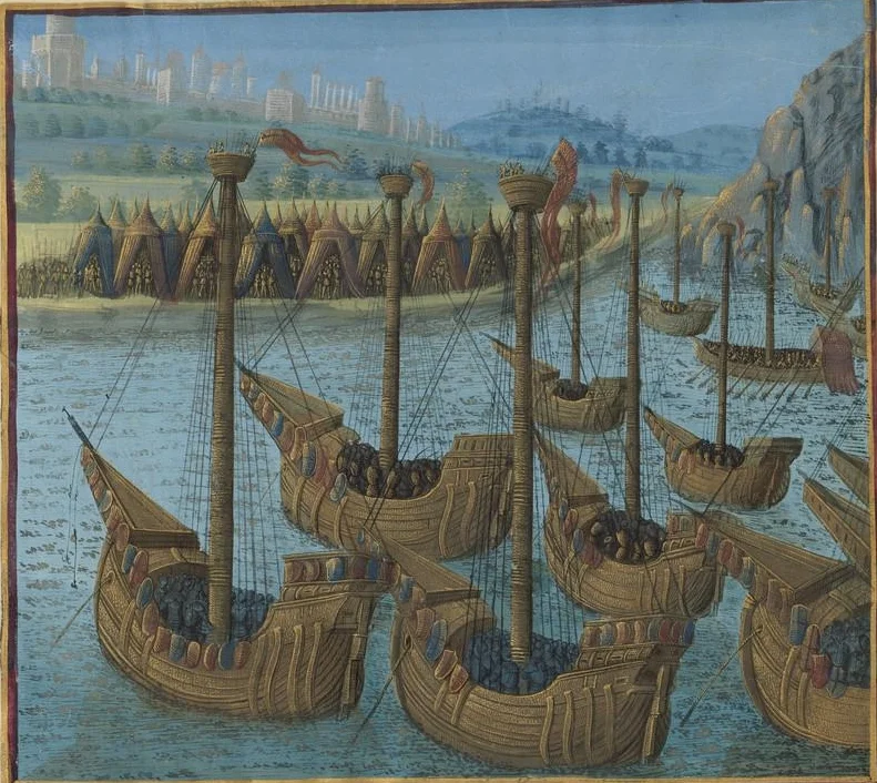 Enluminure médiévale représentant une flotte de nefs croisées chargées d’hommes d’armes, voiles et mâts hérissés de bannières, mouillant près d’un camp de tentes au pied d’une ville fortifiée.