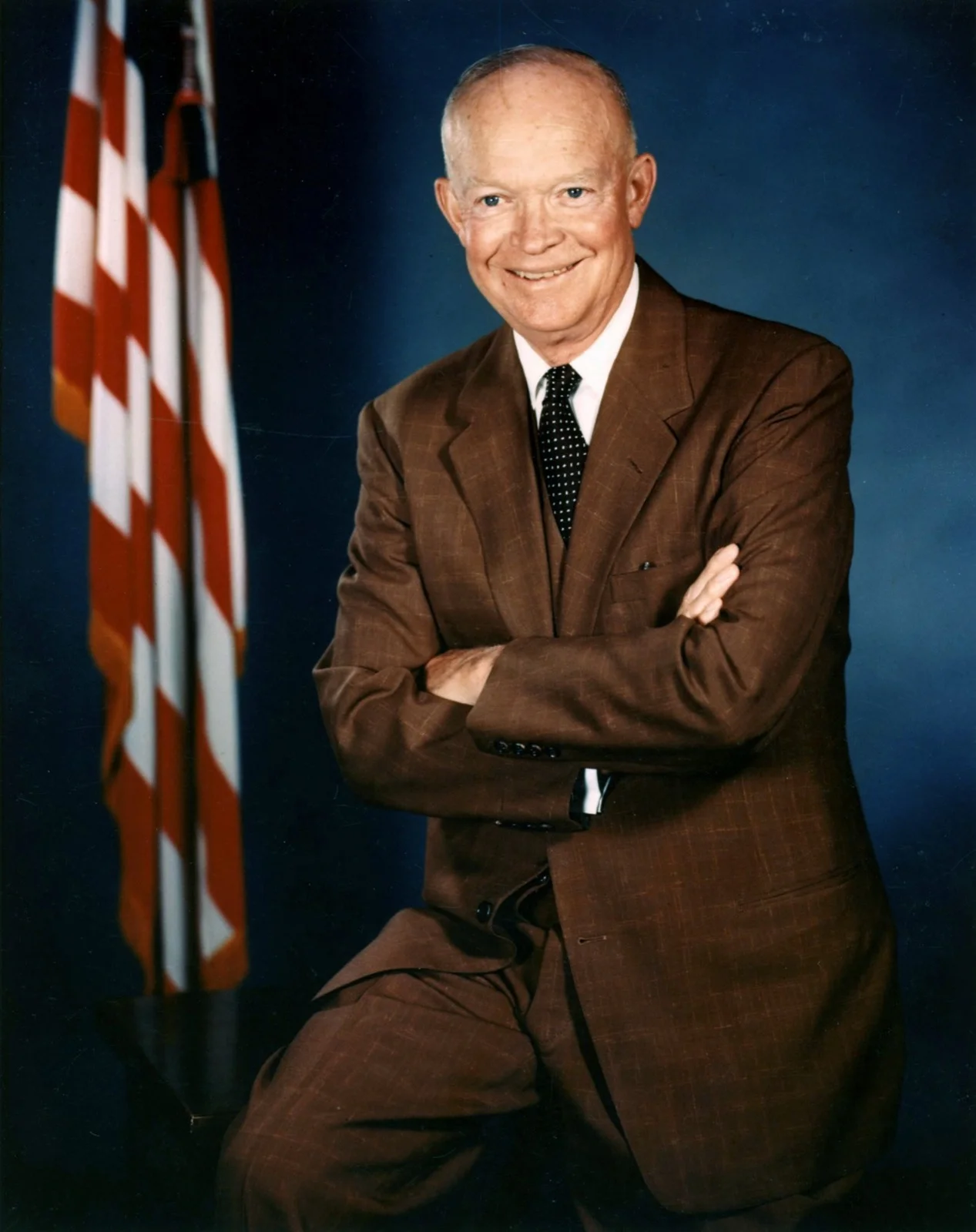 Portrait officiel du président Dwight D. Eisenhower, bras croisés, devant le drapeau américain, juillet 1956.
