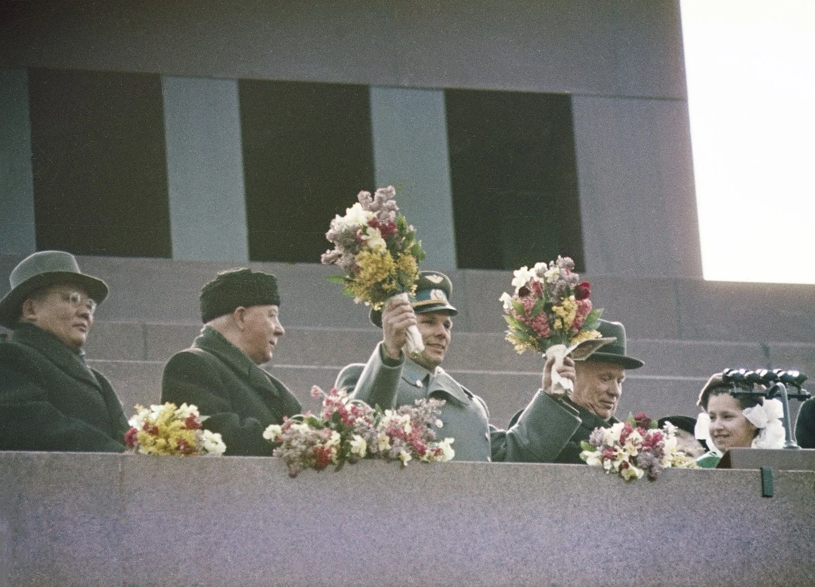 Youri Gagarine, en uniforme et brandissant un bouquet, salue la foule depuis la tribune du mausolée de Lénine sur la place Rouge, aux côtés de Nikita Khrouchtchev, le 14 avril 1961.