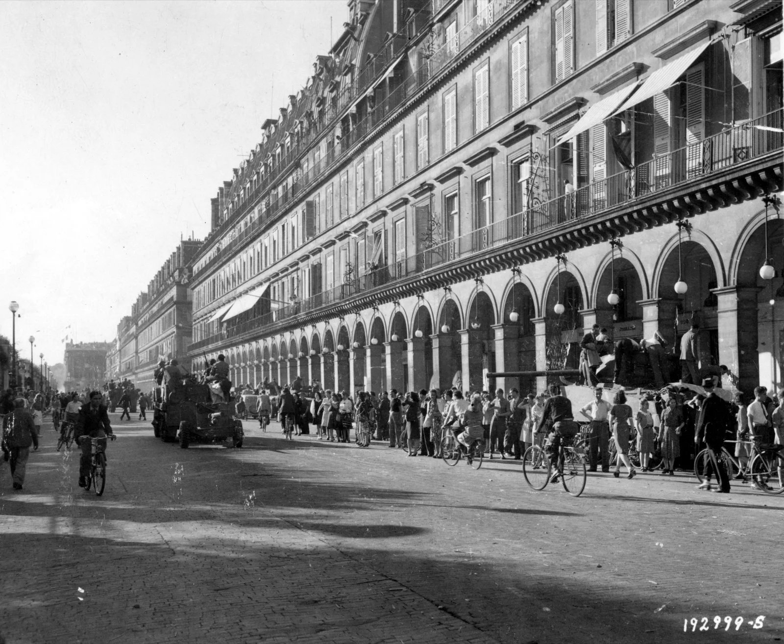 Blindés américains et français de la 2e DB remontant la rue de Rivoli à Paris, le 26 août 1944, acclamés par une foule de Parisiens massée sous les arcades.