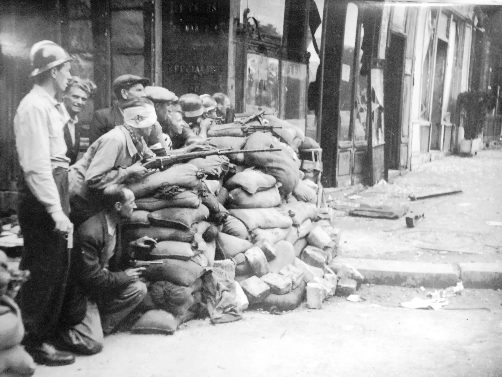 Des résistants FFI et civils armés en position derrière une barricade de sacs de sable lors de la libération de Paris, août 1944