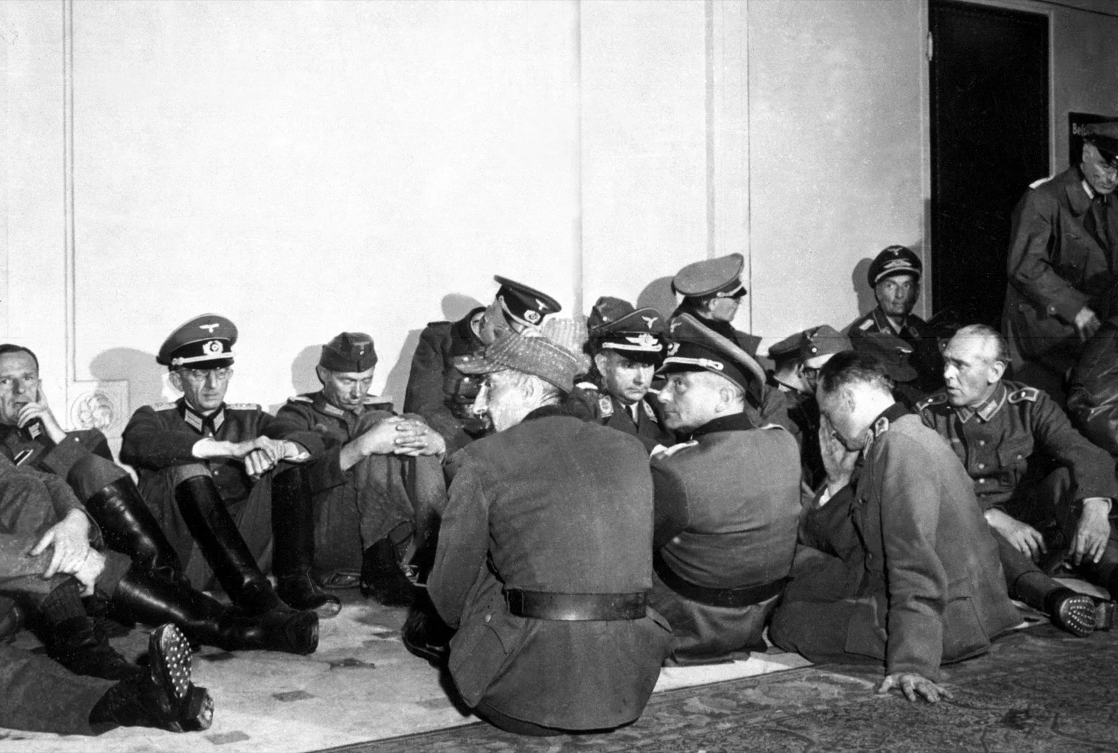 Officiers allemands faits prisonniers, assis au sol et le long d'un mur, gardés dans Paris libéré, fin août 1944.