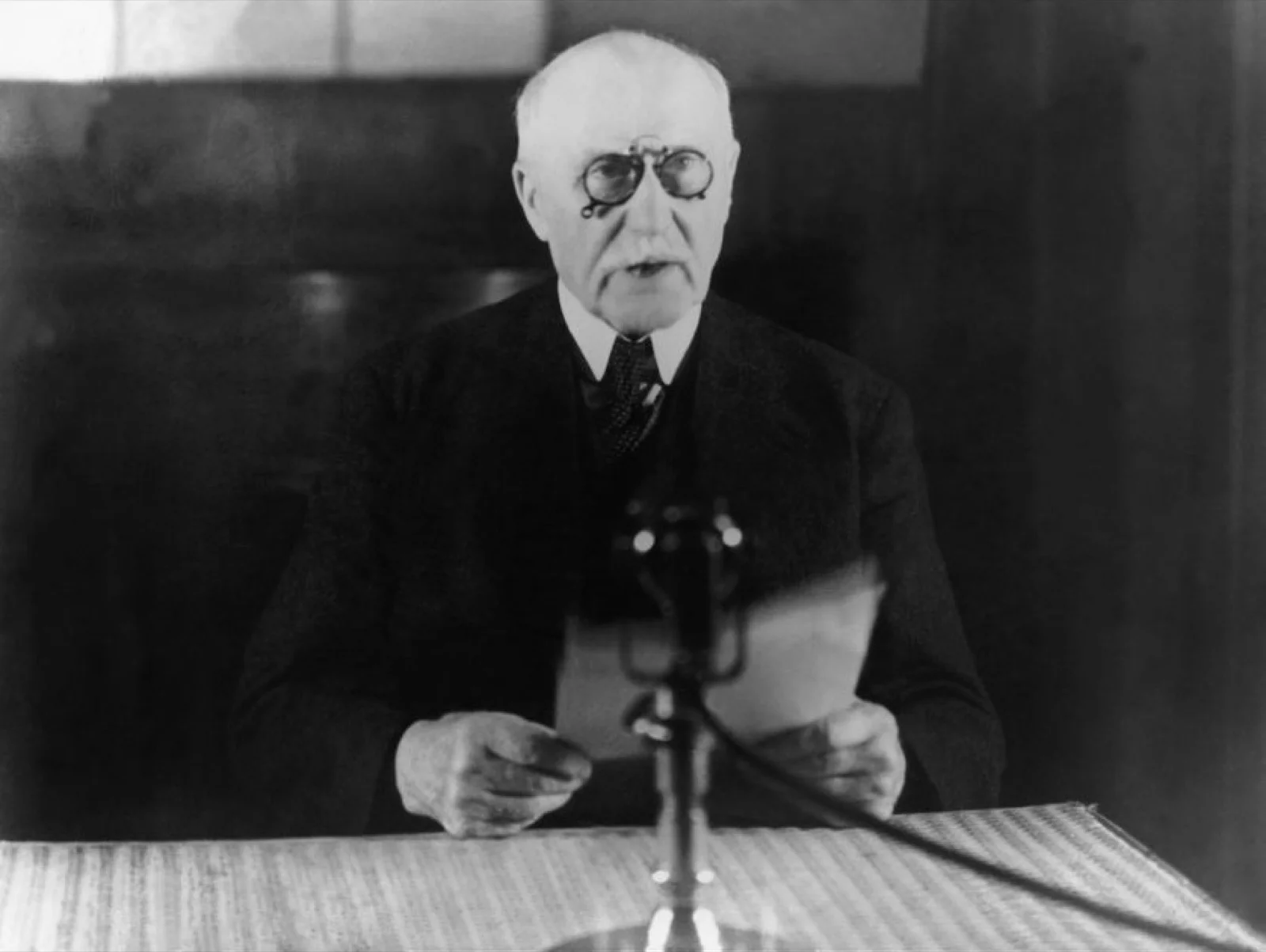 Le maréchal Pétain lisant un discours devant un microphone de radiodiffusion.