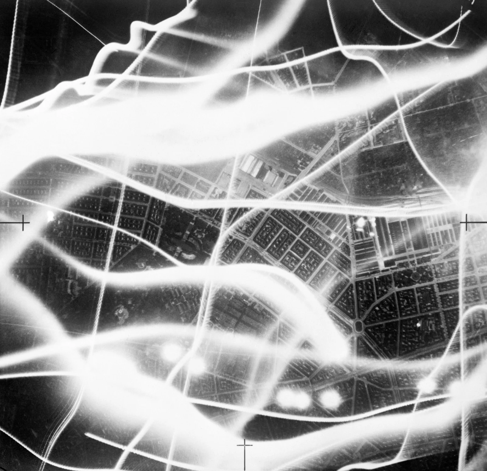 Photographie aérienne nocturne montrant les traînées de projecteurs de DCA et les tirs anti-aériens, 1941.