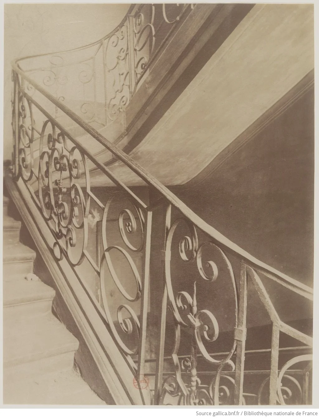 Cage d’escalier d’un immeuble parisien avec rampe en fer forgé ouvragé, vers 1900
